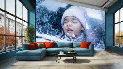 Little girl wearing in winter clothes pressed her face against car window glass funny flattening nose, family road trip in winter, active weekend Wall mural