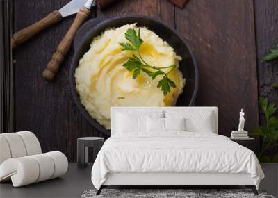 Mashed potatoes or boiled puree with parsley  in cast iron pot on dark wooden rustic background.  top view Wall mural