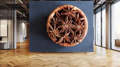 Anise stars closeup in wooden bowl on dark background Wall mural