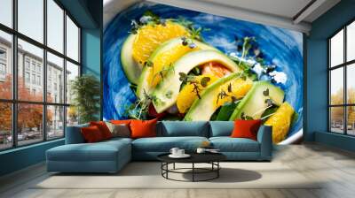 microgreen on avocado, shrimp and orange in blue plate. Wall mural