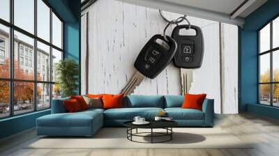 Car keys with electronic fobs hanging on a rustic white wooden surface, symbolizing vehicle ownership and the start of a journey or adventure. Wall mural