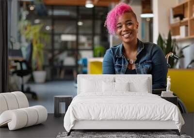 Vibrant and confident, a woman with striking pink hair radiates joy from her wheelchair in a modern, plant-filled office space, embodying inclusivity and positivity. Wall mural