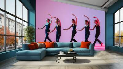 ?hildren dancing. Group of children, little girls in sportive style clothes dancing in studio isolated on background in neon light. Wall mural