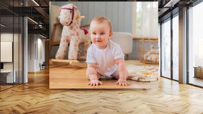 A baby is crawling on the floor in front of a rocking horse. Wall mural