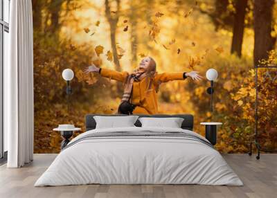 A girl in a yellow coat walks in an autumn park Wall mural