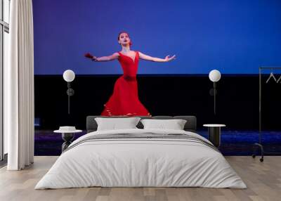 ballerina in a red dress performs a variation from the ballet Don Quixote on the theater stage. Wall mural