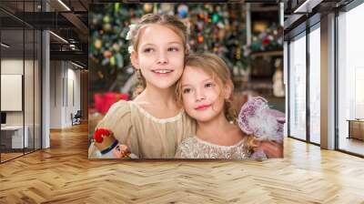 Two smartly dressed girls are playing a Christmas tale at home. Wall mural