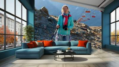 Middle-aged attractive woman mountain portrait. Healthy lifestyle. Beautiful female person. Trekking of mature woman with dslr camera. Solo tourist in the Alps Wall mural