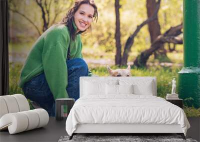 Portrait of a caucasian woman in green sweater and with corgi dog in a park Wall mural