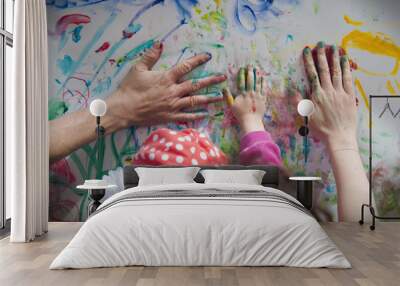 Family draws hands covered in paint. Father, mother and child leave hand prints. Wall mural