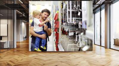 Father and his son choosing the right tool in a hardware store Wall mural