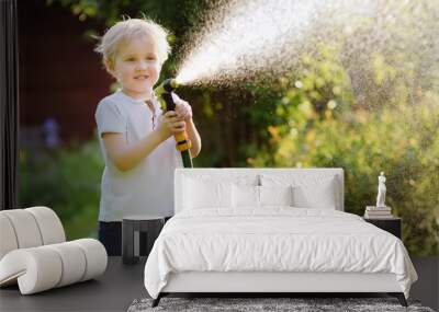 Funny little boy playing with garden hose in sunny backyard Wall mural