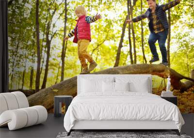 Little boy having fun with mature father during stroll in the forest at sunny autumn day. Active family time on nature. Wall mural