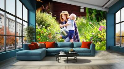 toddler boy and his mother watering plants in the garden Wall mural