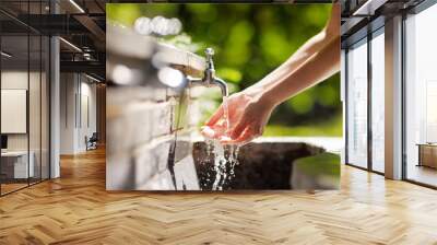 Woman washing hands in a city fountain Wall mural