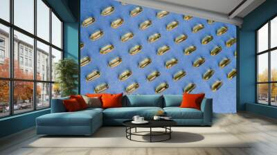 Yellow capsules with vitamin D on a blue background. Sunshine vitamin. Wall mural