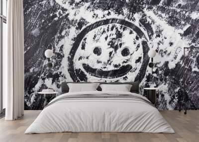 Smiling face drawn with finger on flour scattered on black table Wall mural