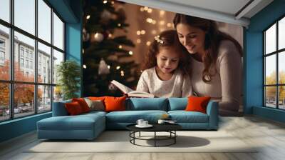 A mother and daughter reading a book in front of a christmas tree Wall mural