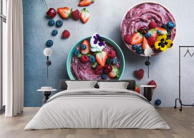 Two summer acai smoothie bowls with strawberries, blueberries,   on gray concrete background. Breakfast bowl with fruit and cereal, close-up, top view, healthy food Wall mural