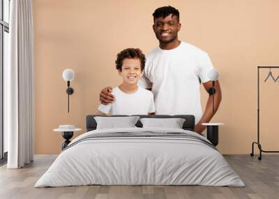 Attractive, young African American man, father and his little son wearing white t shirts hugging Wall mural