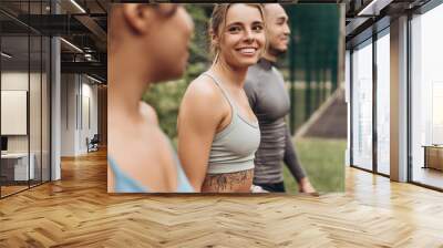 Beautiful, smiling woman talking with diverse sportspeople, walking, training together on the street Wall mural