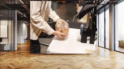 Customer holding loaf of bread at grocery store checkout Wall mural