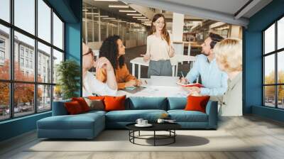 Group of confident business people,  colleagues talking, brainstorming, planning startup working in modern office. Businesswoman explaining something. Teamwork, meeting, seminar, successful business  Wall mural