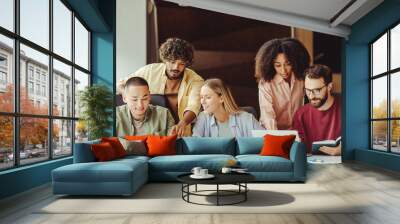 Group of smiling multiracial university students using laptop studying  together, education concept. Young startup team, colleagues meeting, working, planning strategy in office. Successful business Wall mural