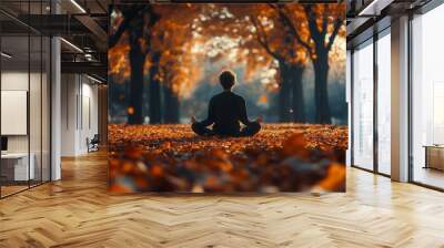 Man meditating in autumn park practicing yoga outdoors Wall mural