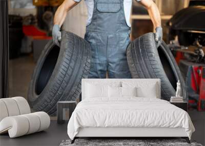 Mechanic holding two tires for seasonal change in workshop Wall mural