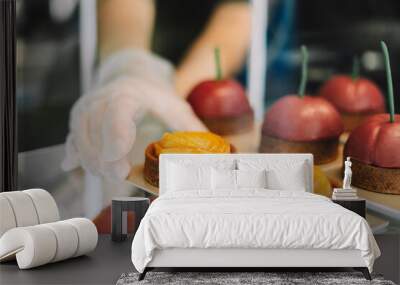 Pastry chef arranging delicious desserts on display in bakery selective focus Wall mural