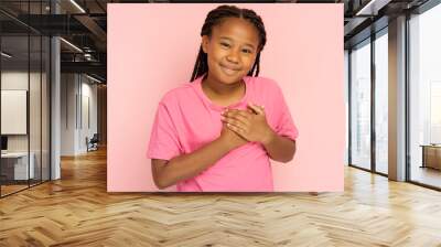 Portrait of attractive little African American girl wearing stylish casual t shirt holding hands over heart Wall mural