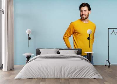 Portrait of handsome smiling bearded man wearing autumn yellow sweater, stylish jeans isolated on blue background. Portrait of successful middle aged fashion model posing for pictures, studio shot Wall mural