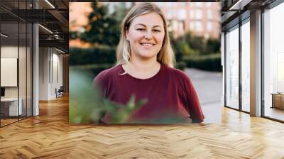 Portrait of happy pretty woman looking at camera in the city Wall mural