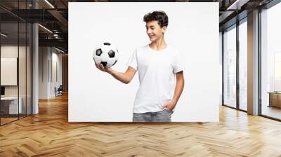 Portrait of smiling adult teenage boy wearing casual clothes holding soccer ball looking away Wall mural