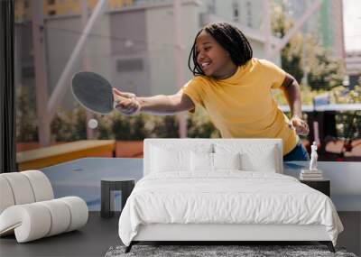 Smiling, attractive African American girl playing ping pong outdoors on sunny summer day Wall mural