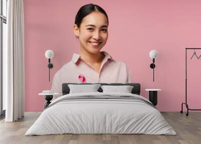 Smiling asian woman smiling wearing pink ribbon showing support for breast cancer awareness Wall mural