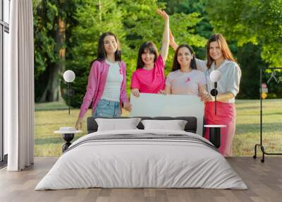 Smiling women with pink ribbon on t shirts looking at camera and holding mockup canvas Wall mural