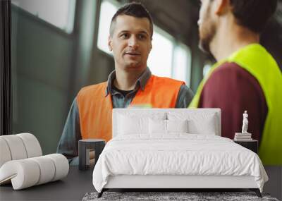 Successful, professional foreman, worker, engineer talking to employee while standing in warehouse Wall mural