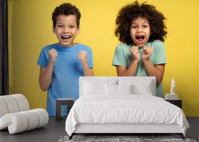 Two happy little African kids rejoicing winner success while standing in studio, looking at camera Wall mural