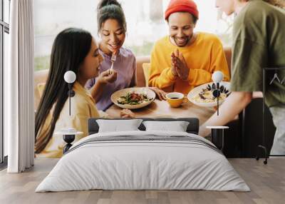 Waitress bringing food to diverse group of friends eating in restaurant Wall mural