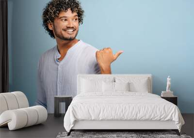 Young man pointing Indian and smiling on copy space on blue background Wall mural