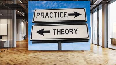 Practice vs theory. White two street signs with arrow on metal pole with word. Directional road. Crossroads Road Sign, Two Arrow. Blue sky background. Two way road sign with text. Wall mural