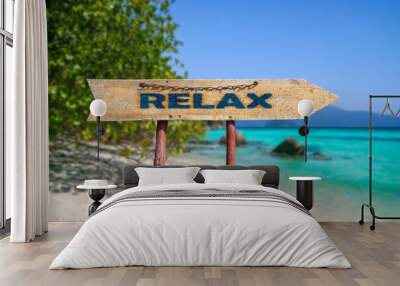 Relax wooden arrow road sign against tropical beach with white sand and turquoise water background. Rest and relaxation concept. Wall mural