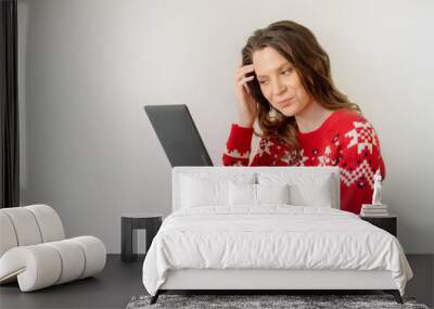 Young caucasian woman in a new year christmas sweater  isolated on white background looking into a tablet buying gifts online Wall mural