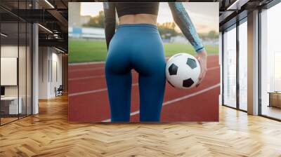 Young slender woman holding soccer ball near buttocks
 Wall mural