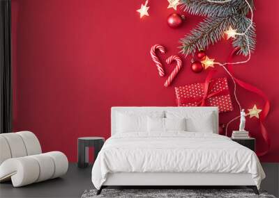 Flat lay border with branches spruce,christmas red balls and gift box on a red background Wall mural