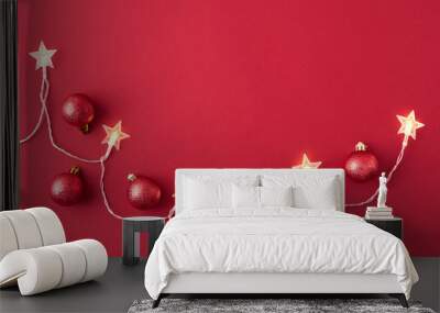 Flat lay frame with christmas garland and red christmas balls on a red background Wall mural