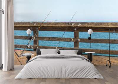 Fishing poles leaning on a rail on a pier in Ventura Los Angeles California Wall mural