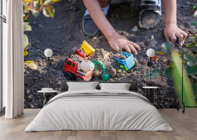 Kid playing with Plastic Toy Tractors in yard Wall mural